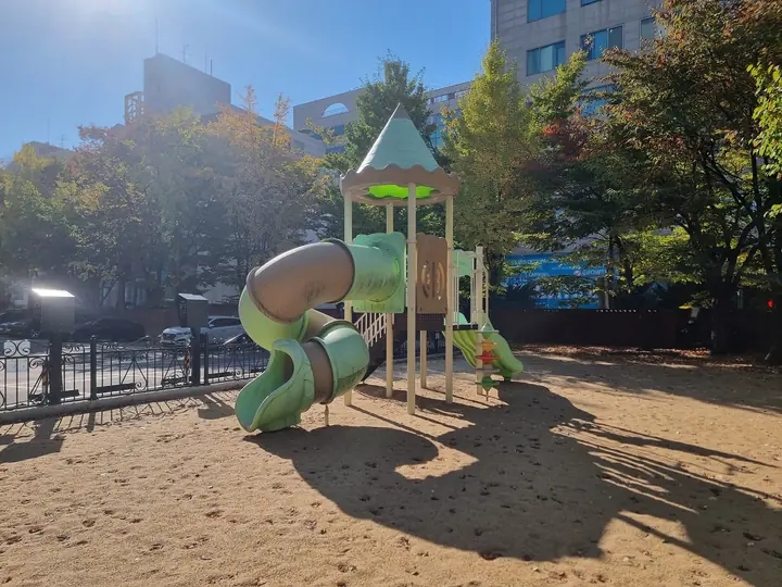초록 터널 미끄럼틀이 있는 모래 놀이터