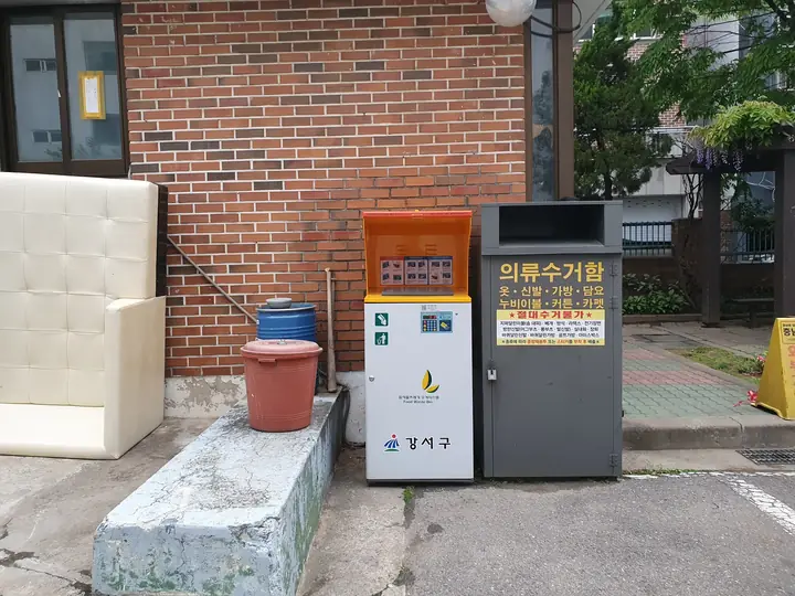 벽돌 벽 앞 의류수거함