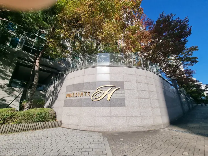 'HILLSTATE' 로고가 붙은 둥근 석재 담장