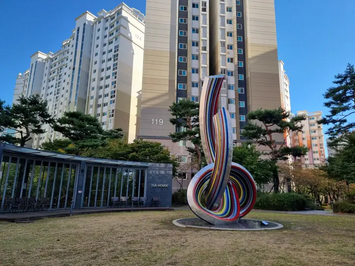 119동 앞 잔디밭의 무지개색 매듭 조형물과 'TEA HOUSE'