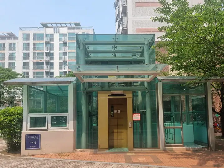 전기차 충전소 안내가 붙은 지하주차장 승강기 출입구