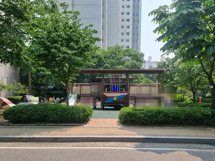 나무 그늘에 둘러싸인 놀이대와 미끄럼틀
