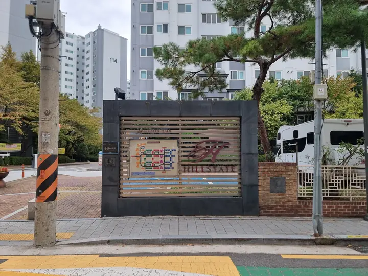 'HILLSTATE' 로고와 안내도를 단 후문 담장