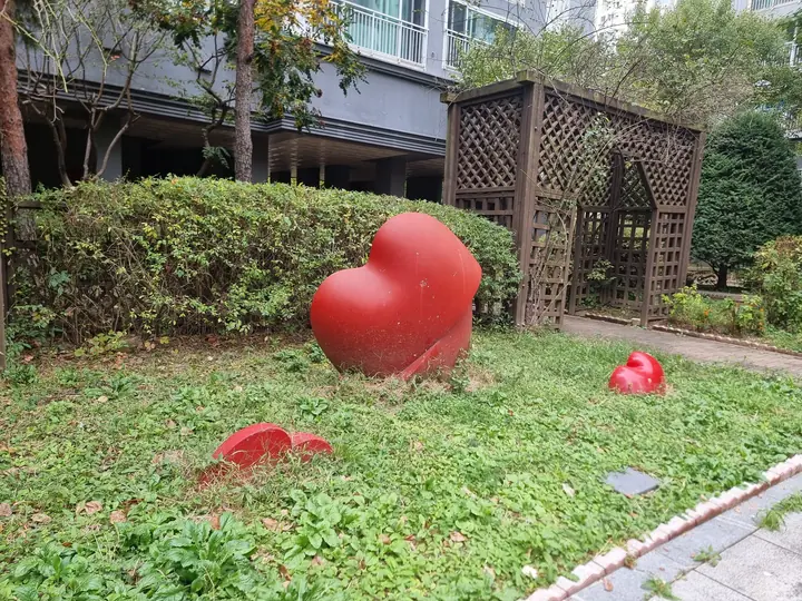 잔디밭 위 빨간 하트 조형물과 목재 트렐리스